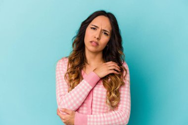 Genç Meksikalı kadın mavi arka planda izole edilmiş dirsek masajı yapıyor, kötü bir hareketin ardından acı çekiyor..