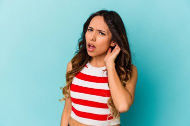Mavi arka planda izole edilmiş genç Meksikalı kadın bir dedikoduyu dinlemeye çalışıyor..