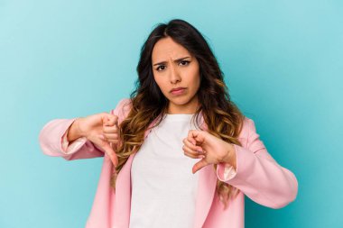 Mavi arka planda izole edilmiş genç Meksikalı kadın baş parmağını aşağı gösteriyor, hayal kırıklığı konsepti.