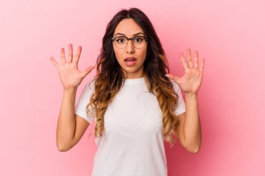 Pembe arka planda izole edilmiş genç Meksikalı kadın gökyüzüne bağırıyor, yukarı bakıyor, hayal kırıklığına uğramış..