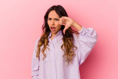 Pembe arka planda izole edilmiş genç Meksikalı kadın baş parmağını aşağı gösteriyor ve hoşlanmadığını ifade ediyor..