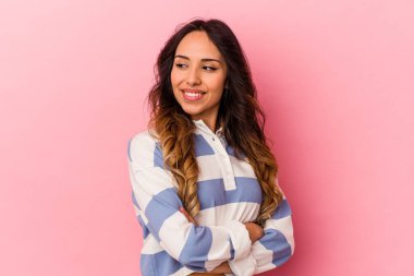 Genç Meksikalı kadın pembe arka planda izole edilmiş gülüyor ve eğleniyor..