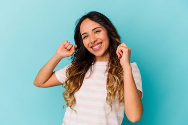 Genç Meksikalı kadın mavi arka planda izole edilmiş dans ediyor ve eğleniyor..