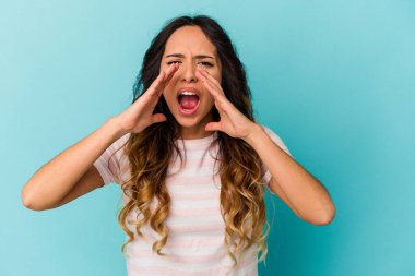 Mavi arka planda izole edilmiş genç Meksikalı kadın heyecanlı bir şekilde bağırıyor..