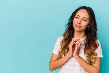 Genç Meksikalı bir kadın mavi arka planda izole edilmiş bir plan yapıyor, bir fikir kuruyor..