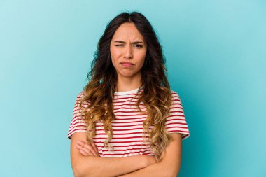 Mavi arka planda izole edilmiş genç Meksikalı kadın alaycı bir ifadeyle kameraya bakarken mutsuz oluyor..