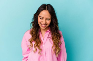 Mavi arka planda izole edilmiş genç Meksikalı kadın gülüyor ve gözlerini kapıyor, rahatlamış ve mutlu hissediyor..