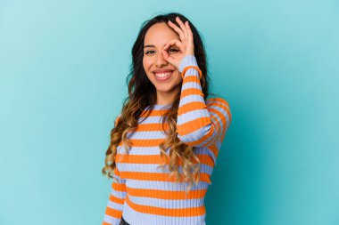 Mavi arka planda izole edilmiş genç Meksikalı kadın heyecanlı..