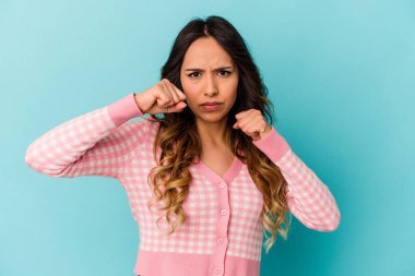 Mavi arka planda izole edilmiş genç Meksikalı kadın bir tartışma yüzünden yumruk, öfke ve kavga atıyor..