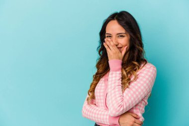 Genç Meksikalı bir kadın mavi arka planda izole edilmiş gülerek, kaygısız, doğal duygularla gülüyor..