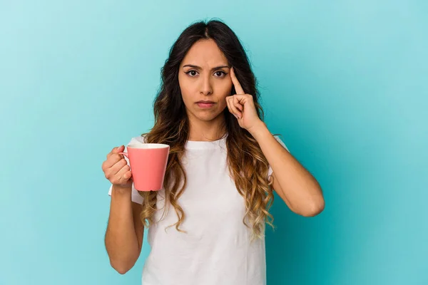 Joven Mexicana Sosteniendo Una Taza Aislada Sobre Fondo Azul Apuntando — Foto de Stock