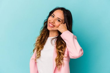 Mavi arka planda izole edilmiş genç Meksikalı kadın parmakları olan bir cep telefonu hareketi gösteriyor..