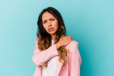 Mavi arka planda izole edilmiş genç Meksikalı kadın omuz ağrısı çekiyor..