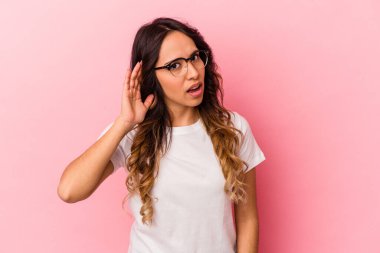 Pembe arka planda izole edilmiş genç Meksikalı kadın bir dedikoduyu dinlemeye çalışıyor..