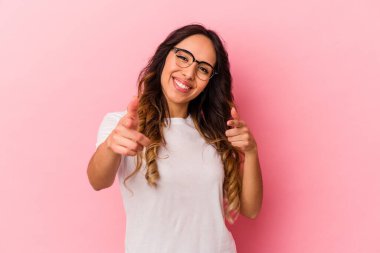 Pembe arka planda izole edilmiş genç Meksikalı kadın gülümsüyor..