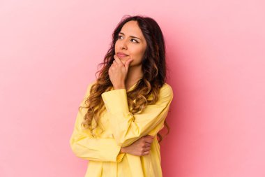Genç Meksikalı kadın pembe arka planda izole edilmiş düşünüyor ve yukarı bakıyor, yansıtıyor, düşünüyor, hayal kuruyor..