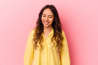 Pembe arka planda izole edilmiş genç Meksikalı kadın gülüyor ve gözlerini kapıyor, rahatlamış ve mutlu hissediyor..
