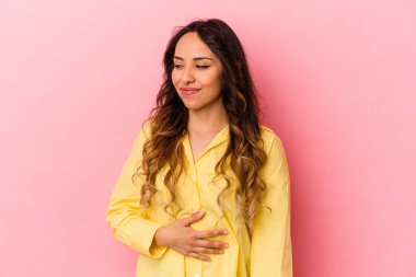 Pembe arka planda izole edilmiş genç Meksikalı kadın karnına dokunuyor, nazikçe gülümsüyor, yemek yiyor ve tatmin oluyor..