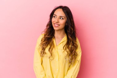 Pembe arka planda izole edilmiş genç Meksikalı kadın gülümseyen, neşeli ve hoş bakışları bir yana bırak..