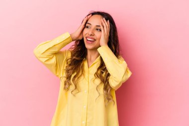 Pembe arka planda izole edilmiş genç Meksikalı kadın mutlu bir şekilde ellerini başının üstünde tutuyor. Mutluluk kavramı.