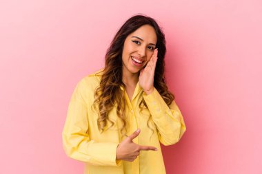 Pembe arka planda izole edilmiş genç Meksikalı bir kadın bir dedikodu söylüyor..