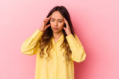 Genç Meksikalı kadın pembe arka planda izole edilmiş tapınaklara dokunuyor ve baş ağrısı çekiyor..