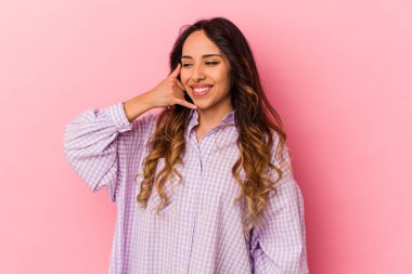 Pembe arka planda izole edilmiş genç Meksikalı kadın parmakları olan bir cep telefonu hareketi gösteriyor..