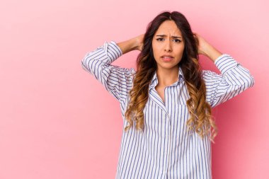 Genç Meksikalı kadın pembe arka planda izole edilmiş kafasının arkasına dokunuyor, düşünüyor ve bir seçim yapıyor..