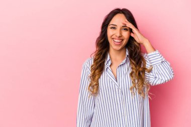 Pembe arka planda izole edilmiş genç Meksikalı kadın yüksek sesle bağırıyor, gözlerini açık ve ellerini gergin tutuyor..