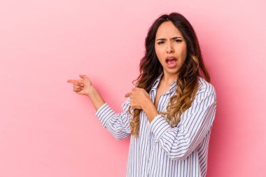 Pembe arka planda izole edilmiş genç Meksikalı kadın işaret parmaklarıyla fotokopi alanını işaret ederek heyecan ve arzusunu ifade ediyor..