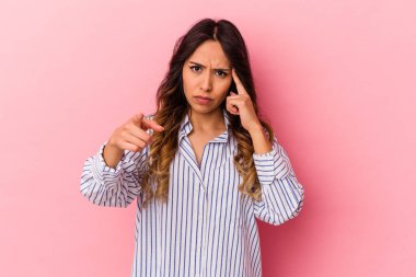 Pembe arka planda izole edilmiş genç Meksikalı kadın parmağıyla tapınağı işaret ediyor, düşünüyor ve bir göreve odaklanıyor..
