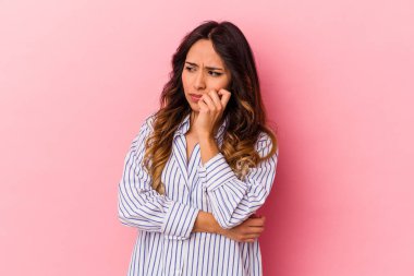 Pembe arka planda izole edilmiş genç Meksikalı kadın kafası karışmış, şüpheli ve güvensiz hissediyor..