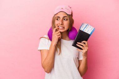 Elinde pasaport ve seyahat biletleri olan beyaz bir kadın pembe arka planda izole edilmiş bir şekilde rahat bir şekilde fotokopi odasına bakan bir şeyi düşünüyor..