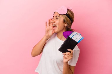 Elinde pasaport ve seyahat biletleri olan beyaz saçlı genç bir kadın pembe arka planda izole edilmiş bir şekilde bağırıyor ve avuç içini açık tutuyordu..