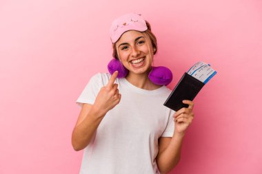 Elinde pasaport ve seyahat biletleri olan beyaz saçlı genç bir kadın pembe arka planda tek başına seni işaret ediyor. Sanki davet ediliyormuş gibi..