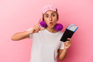 Elinde pasaport ve seyahat biletleri olan beyaz saçlı genç bir kadın pembe arka planda izole edilmiş bir şekilde bir fikri, ilham verici bir konsepti var..