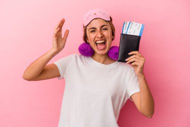 Elinde pasaport ve seyahat biletleri olan beyaz saçlı genç bir kadın pembe arka planda yalnız başına hoş bir sürprizle karşılaşıyor, heyecanlı ve el kaldırıyor..