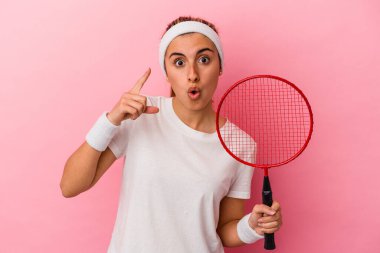 Pembe arka planda soyutlanmış badminton raketi tutan beyaz bir kadın. Bir fikri, ilham verici bir fikri var..