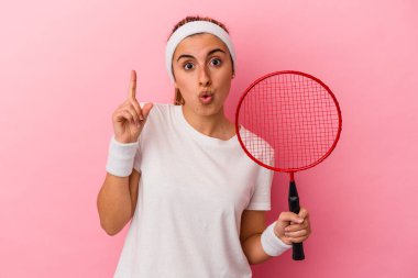 Elinde pembe arka planda izole edilmiş badminton raketi tutan beyaz bir kadın. Harika bir fikir, yaratıcılık kavramı var..