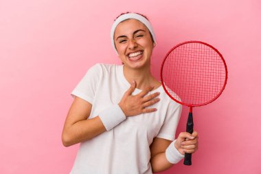 Pembe arka planda izole edilmiş badminton raketi tutan genç, sarışın, beyaz kadın kahkahalar atıyor..