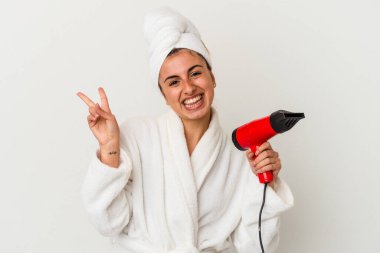 Beyaz, neşeli ve kaygısız bir şekilde izole edilmiş saç kurutma makinesini tutan beyaz bir kadın barış sembolünü parmaklarıyla gösteriyor..