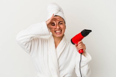 Beyaz tenli beyaz bir kadın elinde saç kurutma makinesi tutuyor. Heyecanlı. Göze göz hareketi yapıyor..