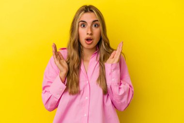 Sarışın, beyaz bir kadın. Sarı arka planda izole edilmiş. Şaşırmış ve şok olmuş..