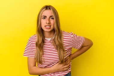 Sarışın, beyaz bir kadın sarı arka planda izole edilmiş, karaciğer ağrısı, karın ağrısı var..