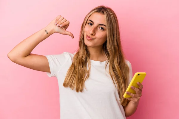 Joven Rubia Caucásica Sosteniendo Teléfono Móvil Amarillo Aislado Siente Orgullosa —  Fotos de Stock