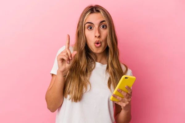 Joven Rubia Caucásica Sosteniendo Teléfono Móvil Amarillo Aislado Teniendo Alguna —  Fotos de Stock