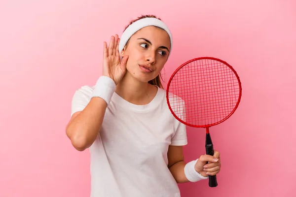 年轻可爱的金发白人女人拿着一个粉色背景的羽毛球拍 想听一些闲话 — 图库照片
