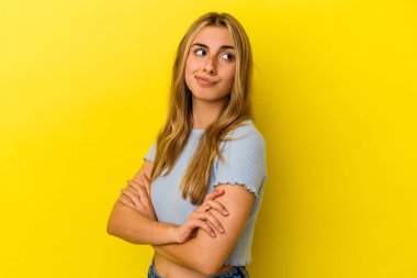 Sarı arka planda izole edilmiş genç sarışın kadın hedeflerine ve amaçlarına ulaşma hayali kuruyor.