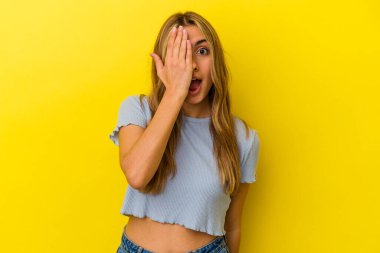 Sarı arka planda izole edilmiş genç sarışın kadın yüzünün yarısını palmiye ile kaplayarak eğleniyor..