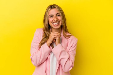 Sarı arka planda izole edilmiş genç sarışın beyaz kadın ellerini çenesinin altında tutuyor, mutlu bir şekilde yana bakıyor..
